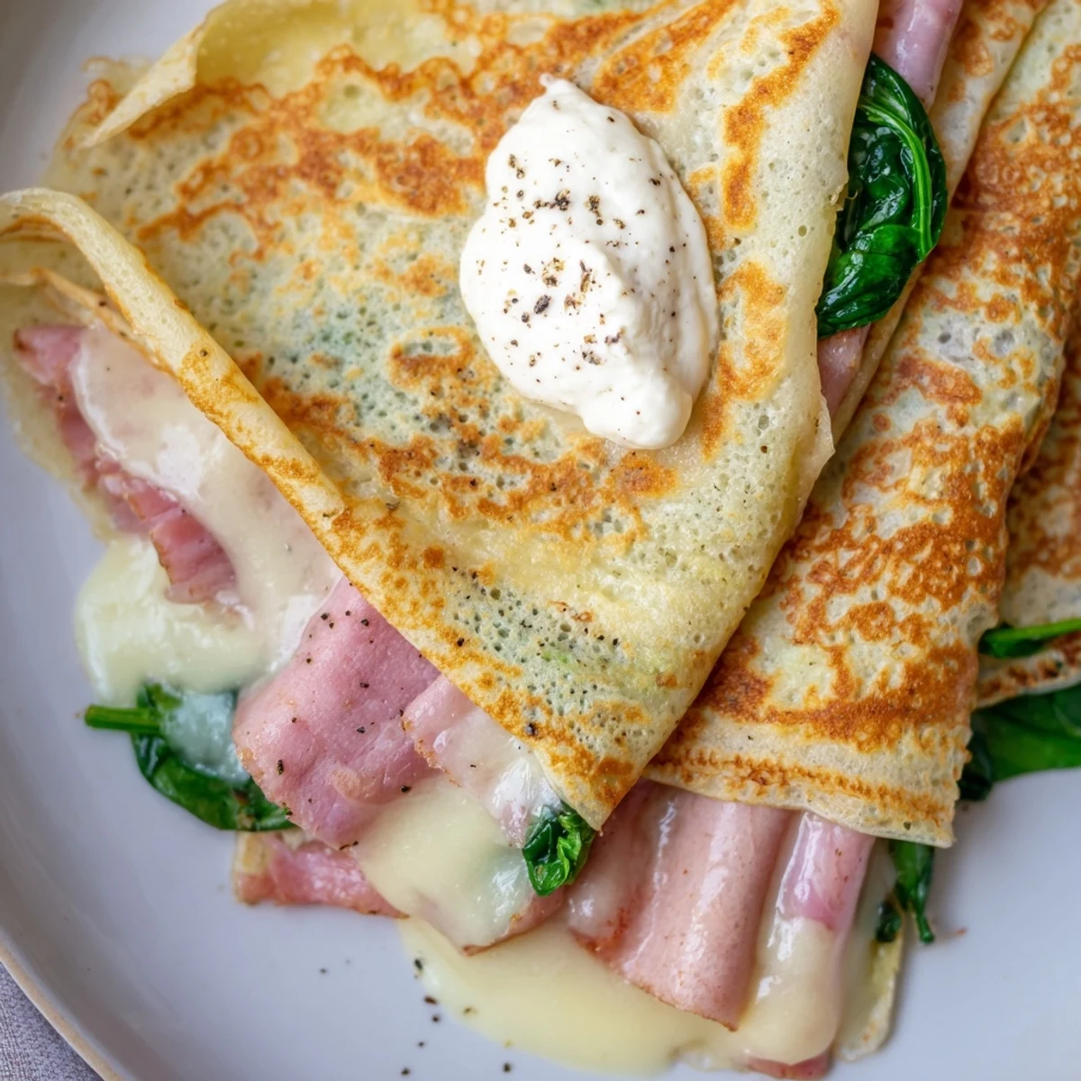 Folded French savory crepes bubbling with hot cheese and fresh spinach filling, ready to serve