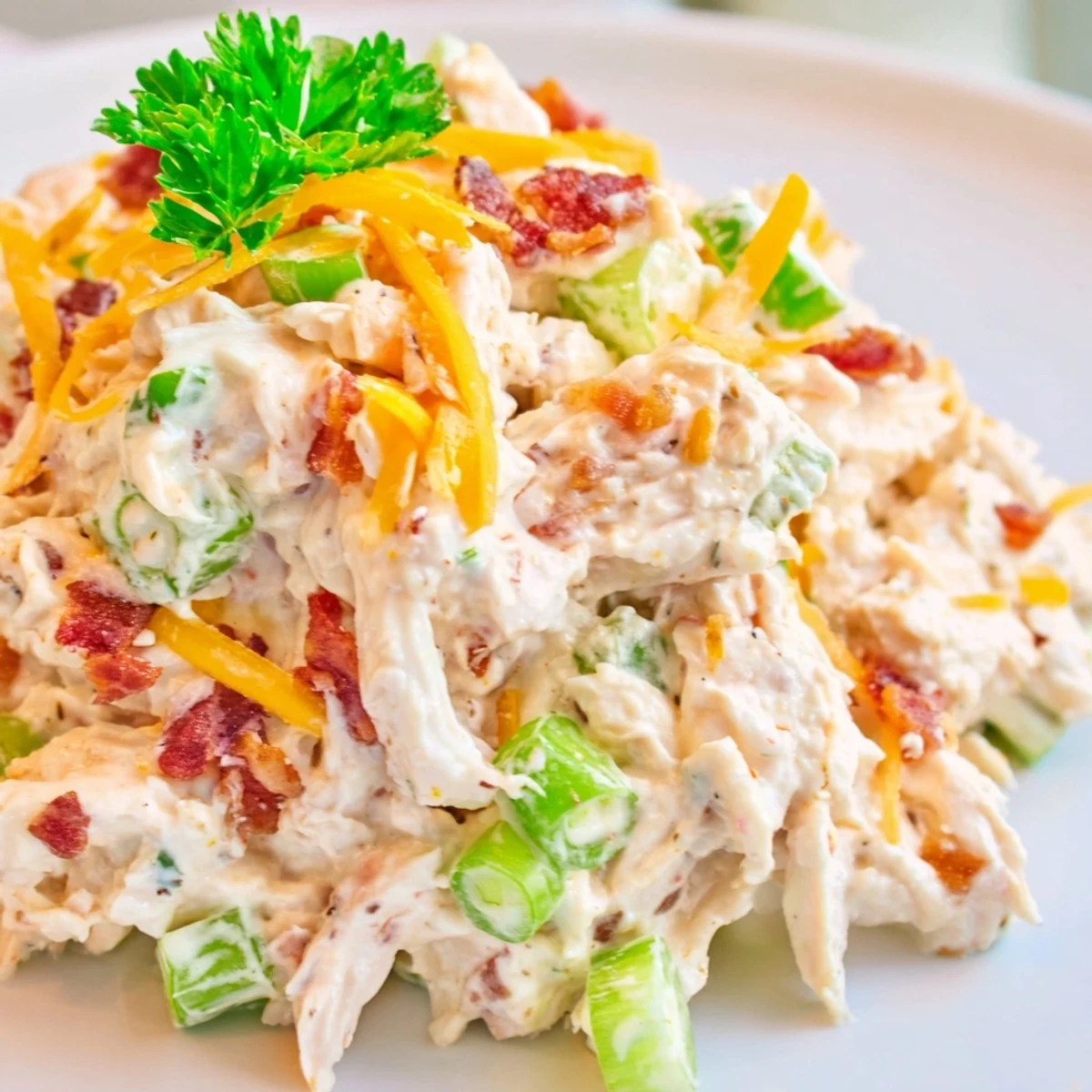 Creamy low carb jalapeno popper cottage cheese chicken salad topped with crispy bacon crumbles and fresh green onions in a white bowl