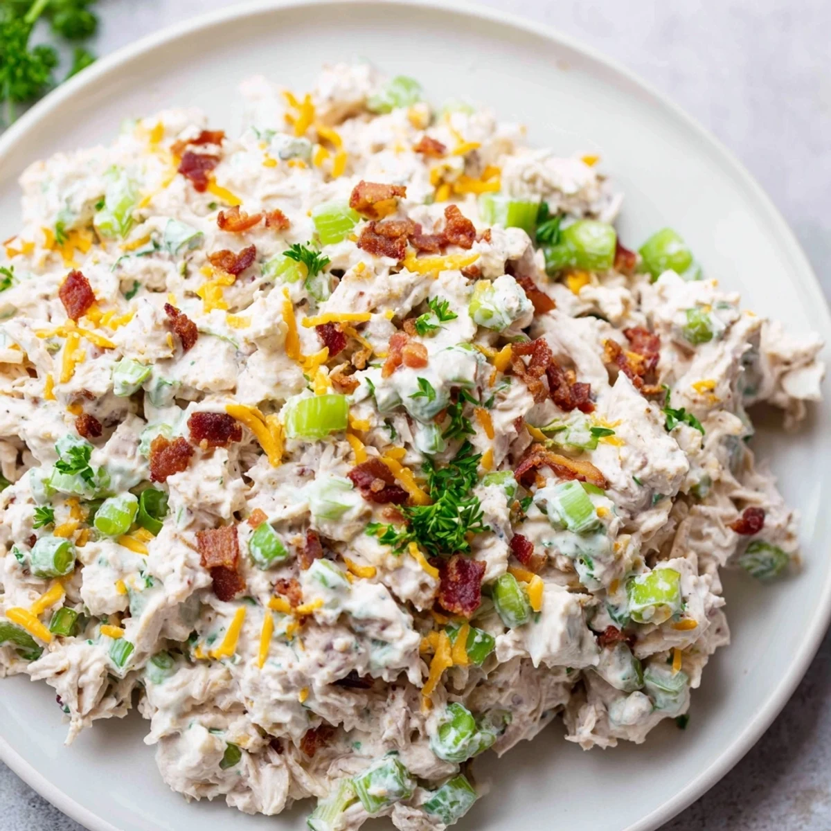 A satisfying high-protein bowl of low carb jalapeno popper cottage cheese chicken salad garnished with chopped parsley and jalapeno slices