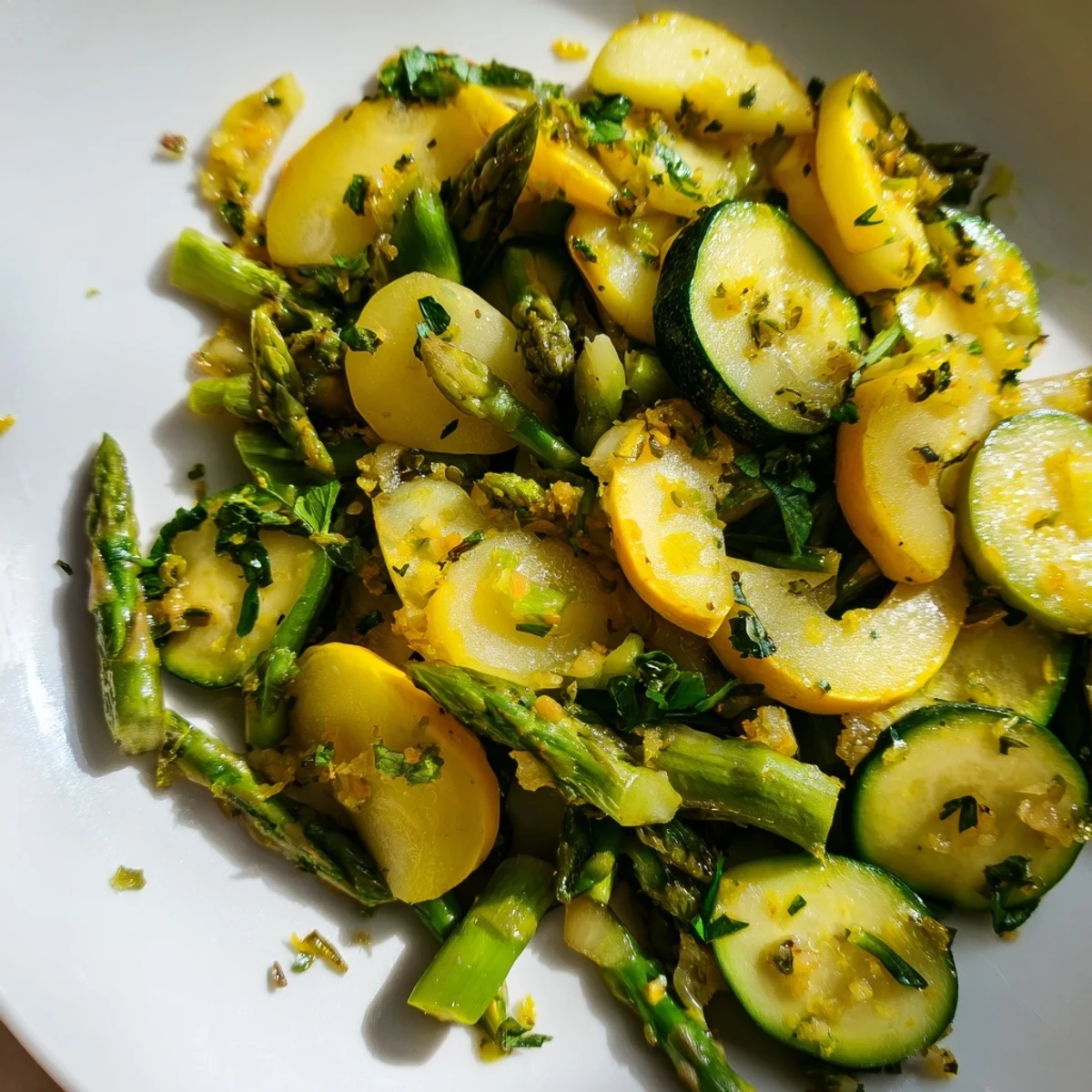 Vibrant medley of tender asparagus, green zucchini, and yellow squash garnished with parsley and lemon zest