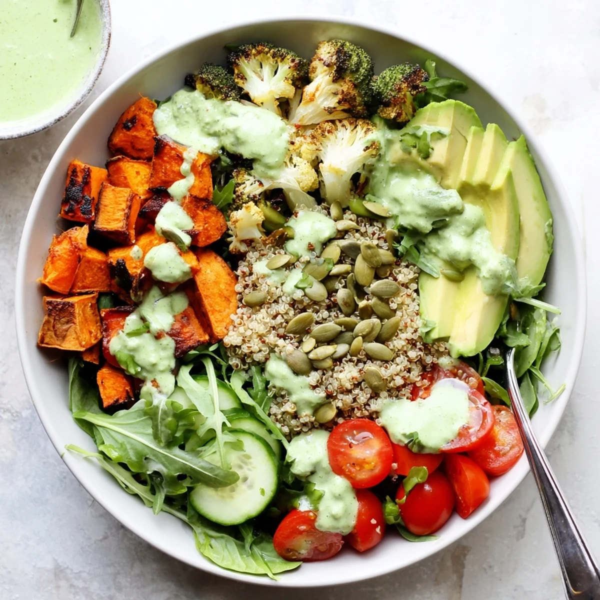 Colorful healthy green goddess veggie bowl with roasted sweet potatoes and creamy herb dressing drizzled over fresh greens
