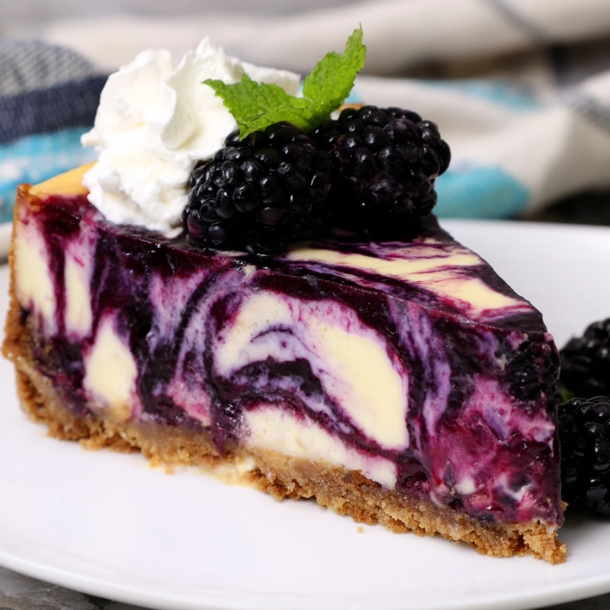 Whole blackberry bliss cheesecake with graham cracker crust garnished with whipped cream