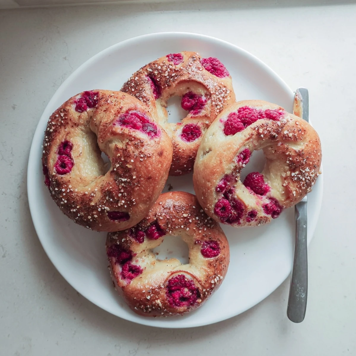 Hand-shaped raspberry sourdough bagels speckled with fruit ready for breakfast with cream cheese spread