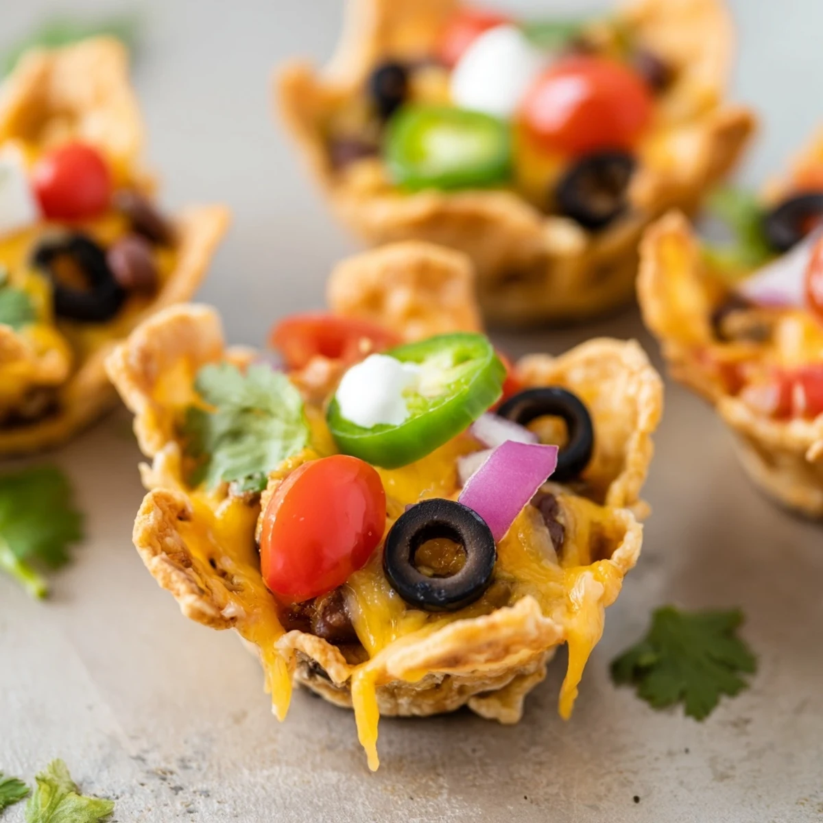 Golden cheesy nacho cups bubbling with melted cheddar and colorful fresh toppings in muffin tin