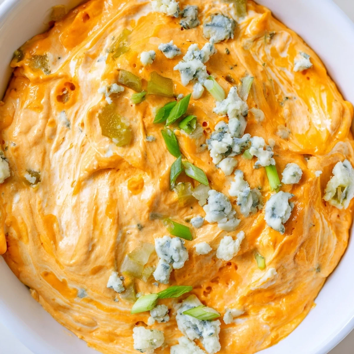 Tangy buffalo pickle dip topped with chopped chives and pickle slices ready for game day snacking spread