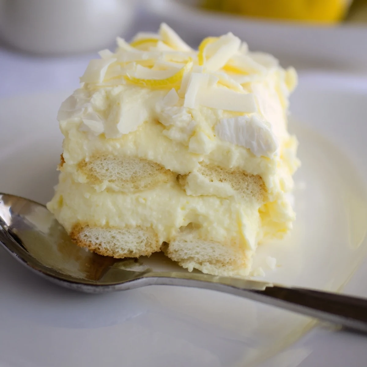 Golden ladyfingers peeking through tangy lemon tiramisu served chilled on a plate