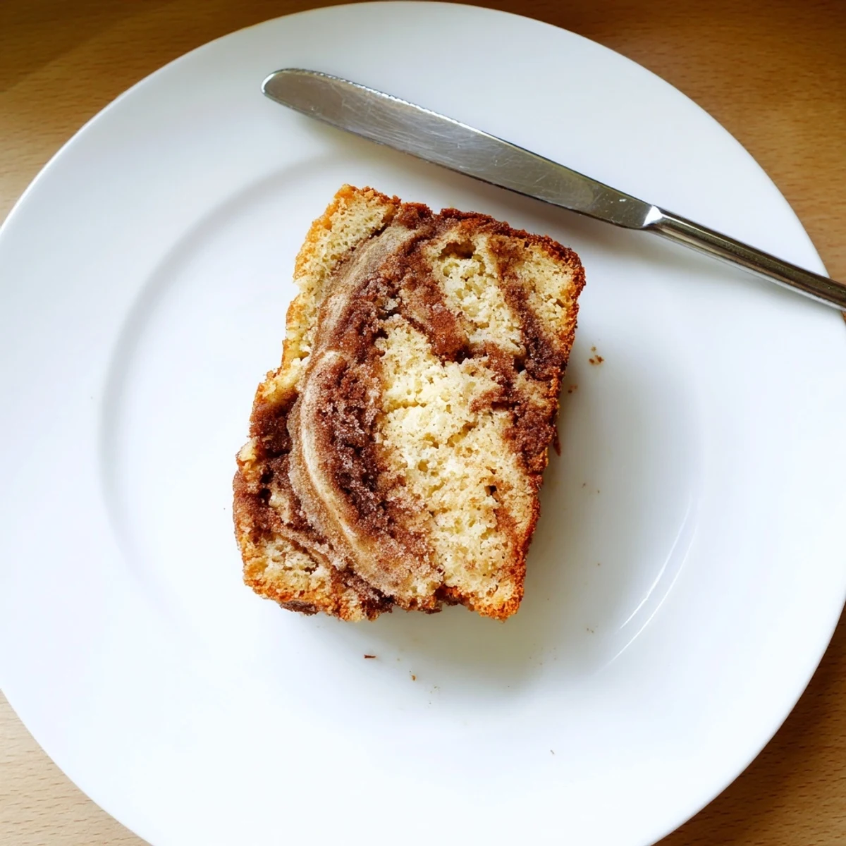 Golden snickerdoodle banana bread slice with a cinnamon-sugar swirl on a plate