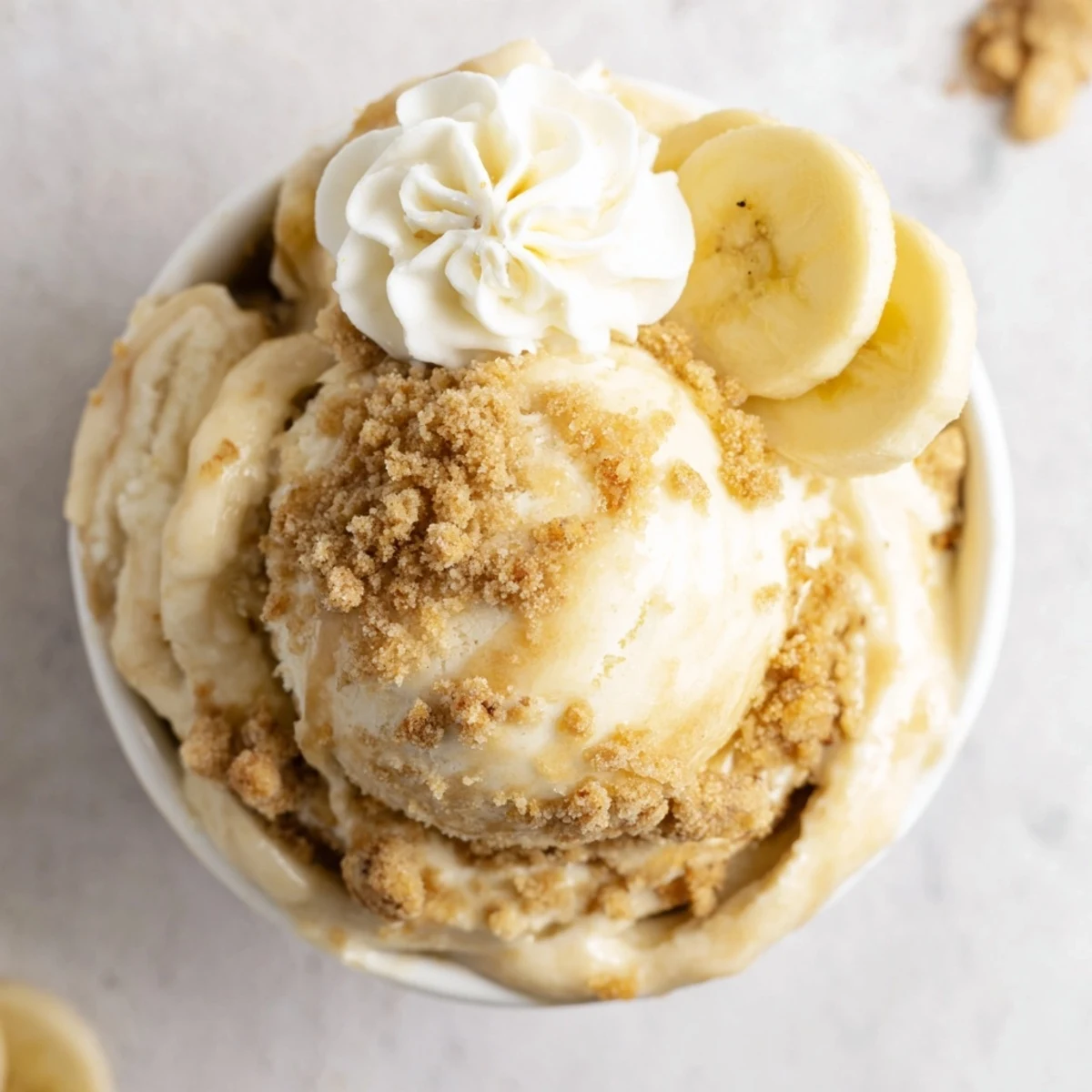 Scoops of Ninja Creami Banana Cream Pie Ice Cream in bowls, banana garnish