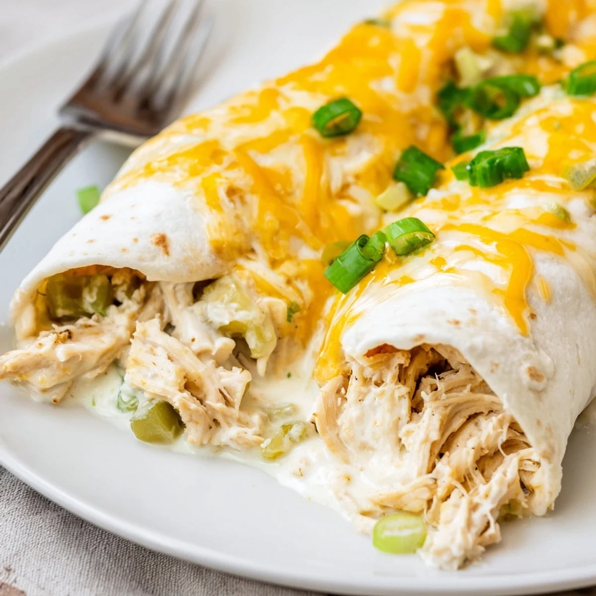 White Rotisserie Chicken Enchiladas bubbling in dish, creamy sauce and melted cheese.