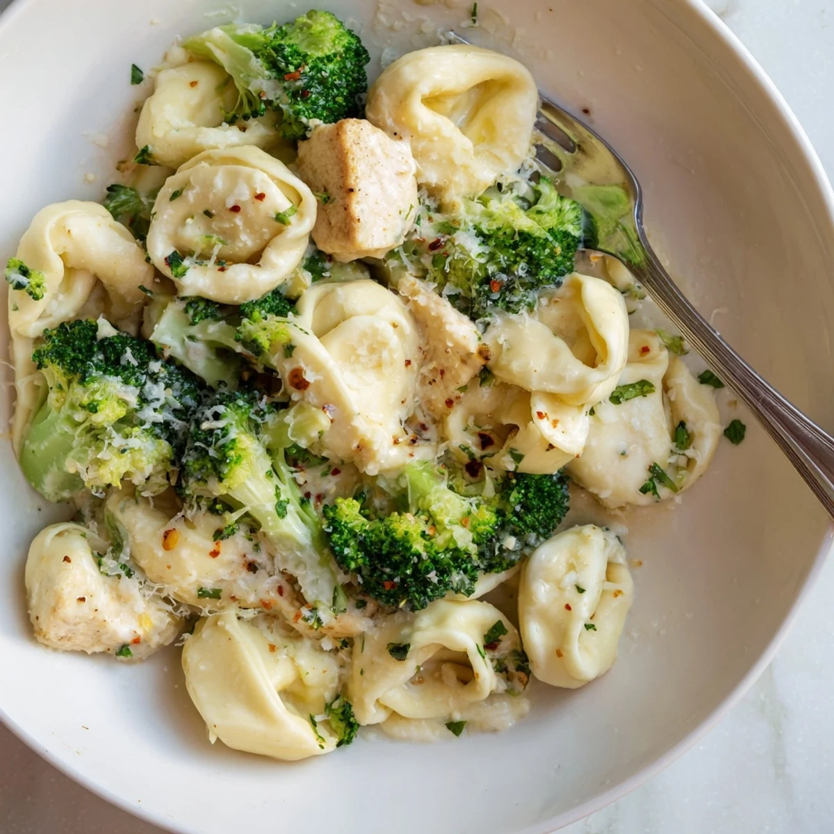 A cozy plate of Creamy Garlic Parmesan Tortellini Chicken Broccoli Recipe garnished with parsley