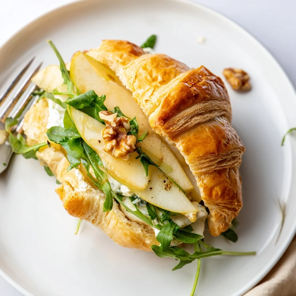 Layered Apple Goat Cheese Croissant Sandwich drizzled with honey, sprinkled walnuts