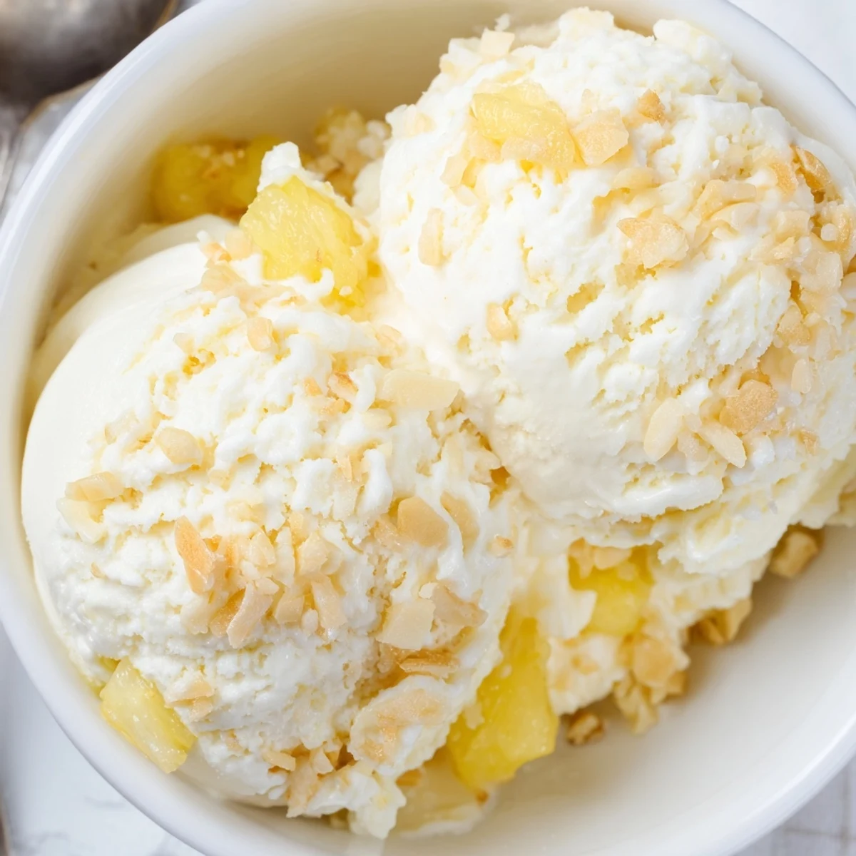 Creamy Pineapple Ice Cream served in a bowl garnished with toasted coconut