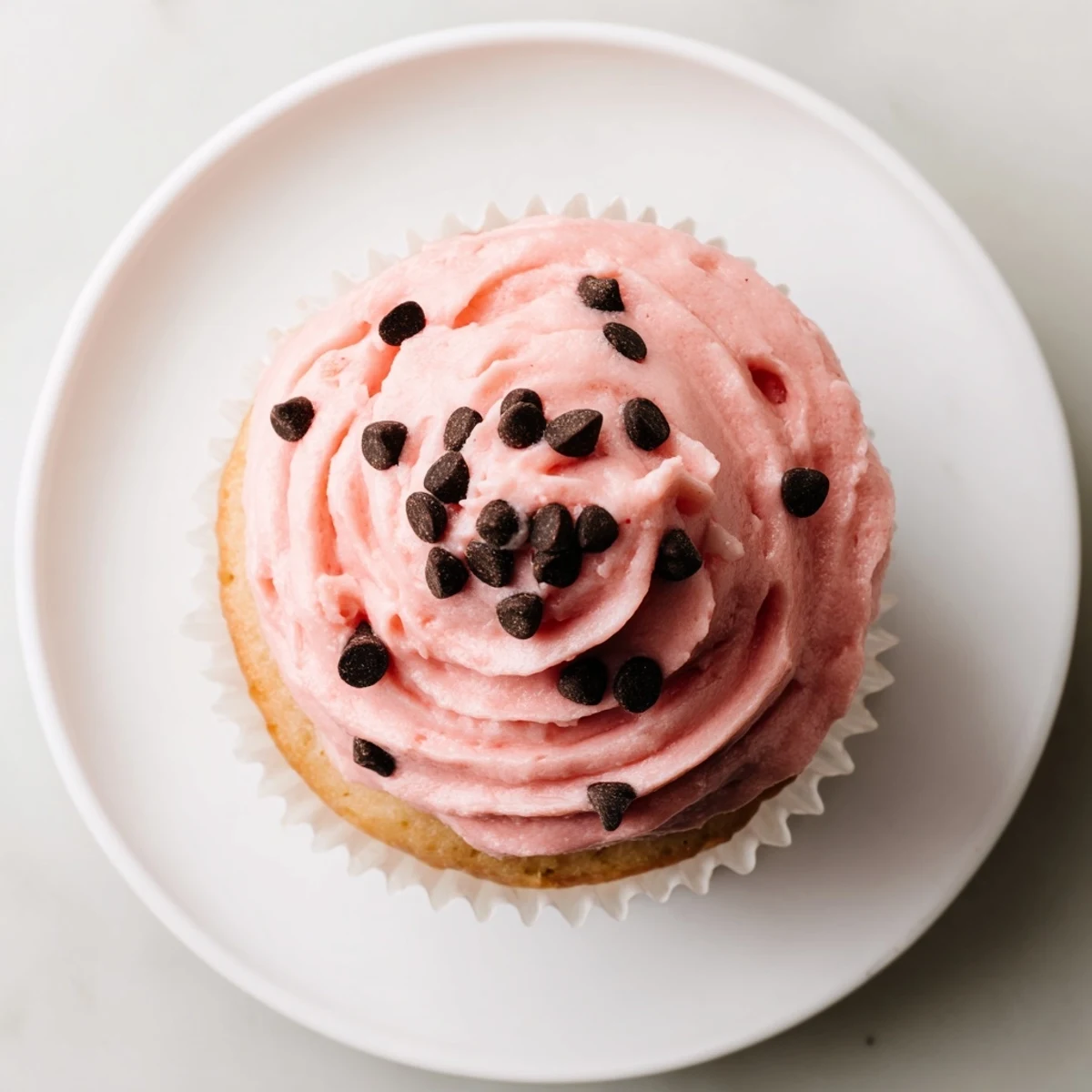 Pink watermelon-frosted vanilla cupcakes decorated with chocolate sprinkles on a bright summer serving platter