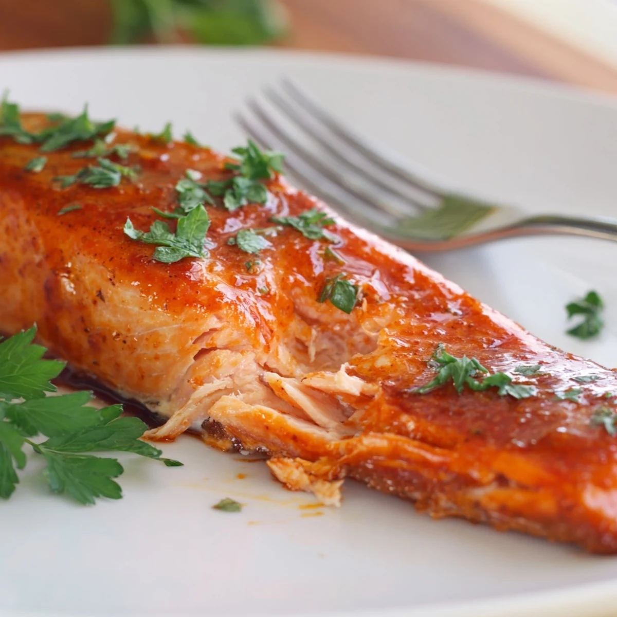 Golden brown Cajun honey salmon fillets with caramelized honey glaze and fresh parsley garnish on a white baking sheet