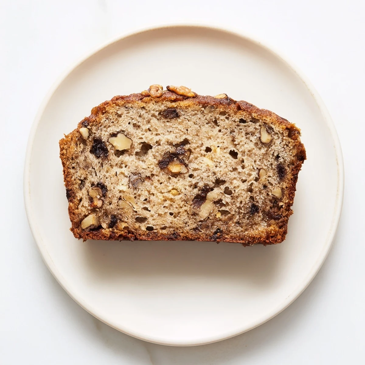 Freshly baked protein banana bread oil free with a perfect golden crust on white plate
