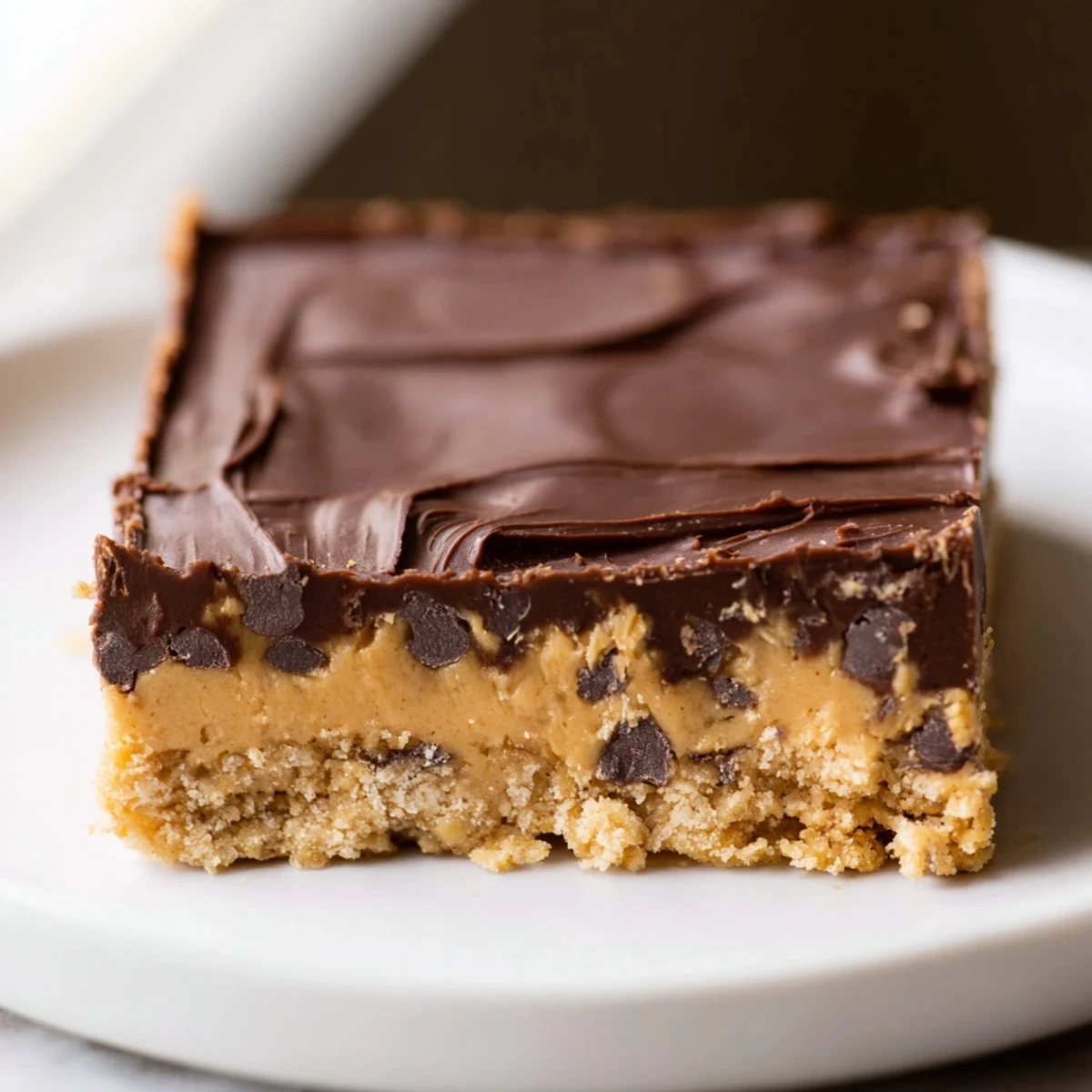 Golden chocolate-topped peanut butter bars arranged on a white serving plate